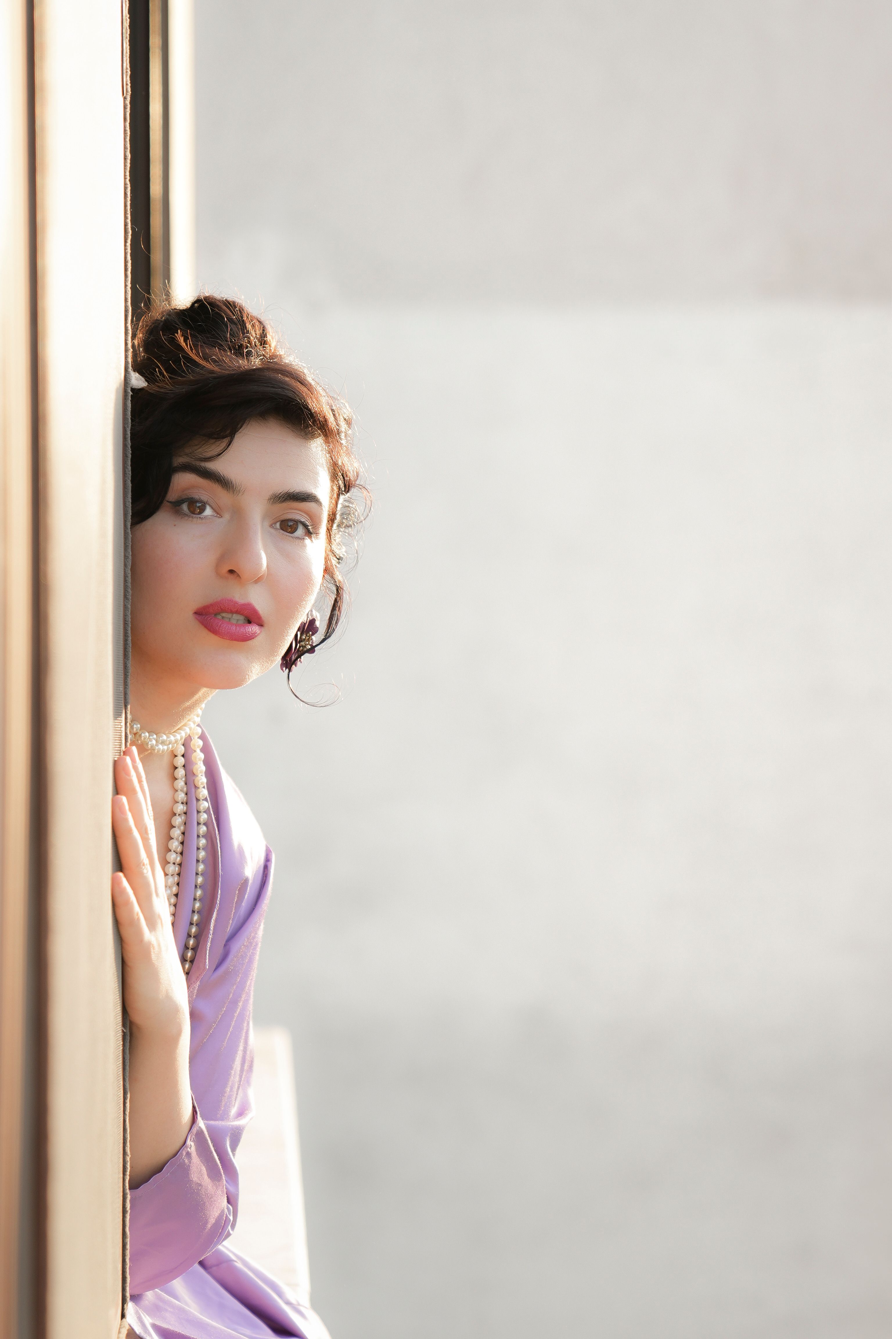 A woman leaning against a wall with her hand on her hip · Free Stock Photo