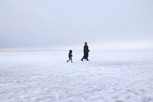 Two People Walking on a Snow-Covered Field
