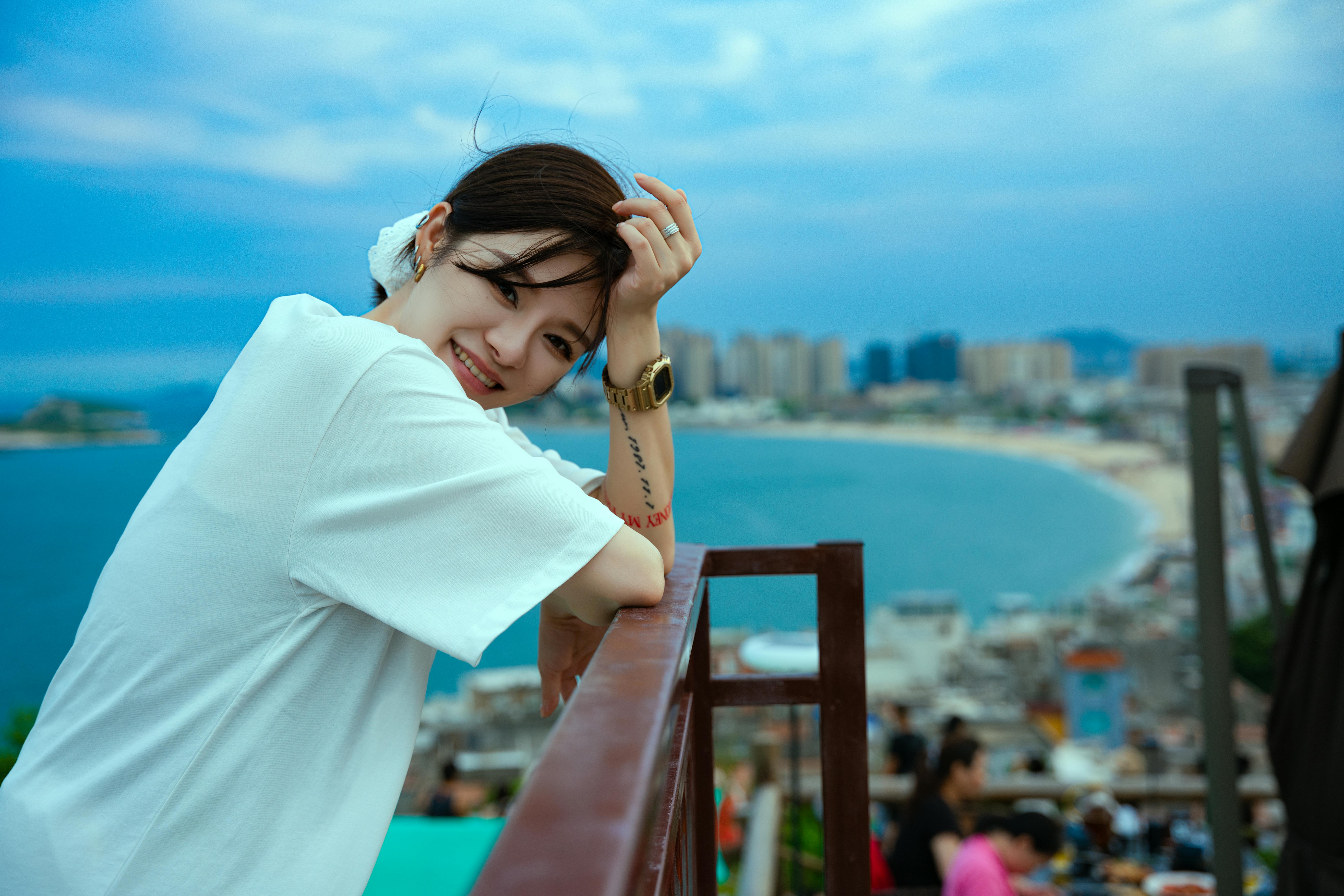 Smiling woman enjoying a beautiful day by the beach, perfect for travel and leisure concepts.