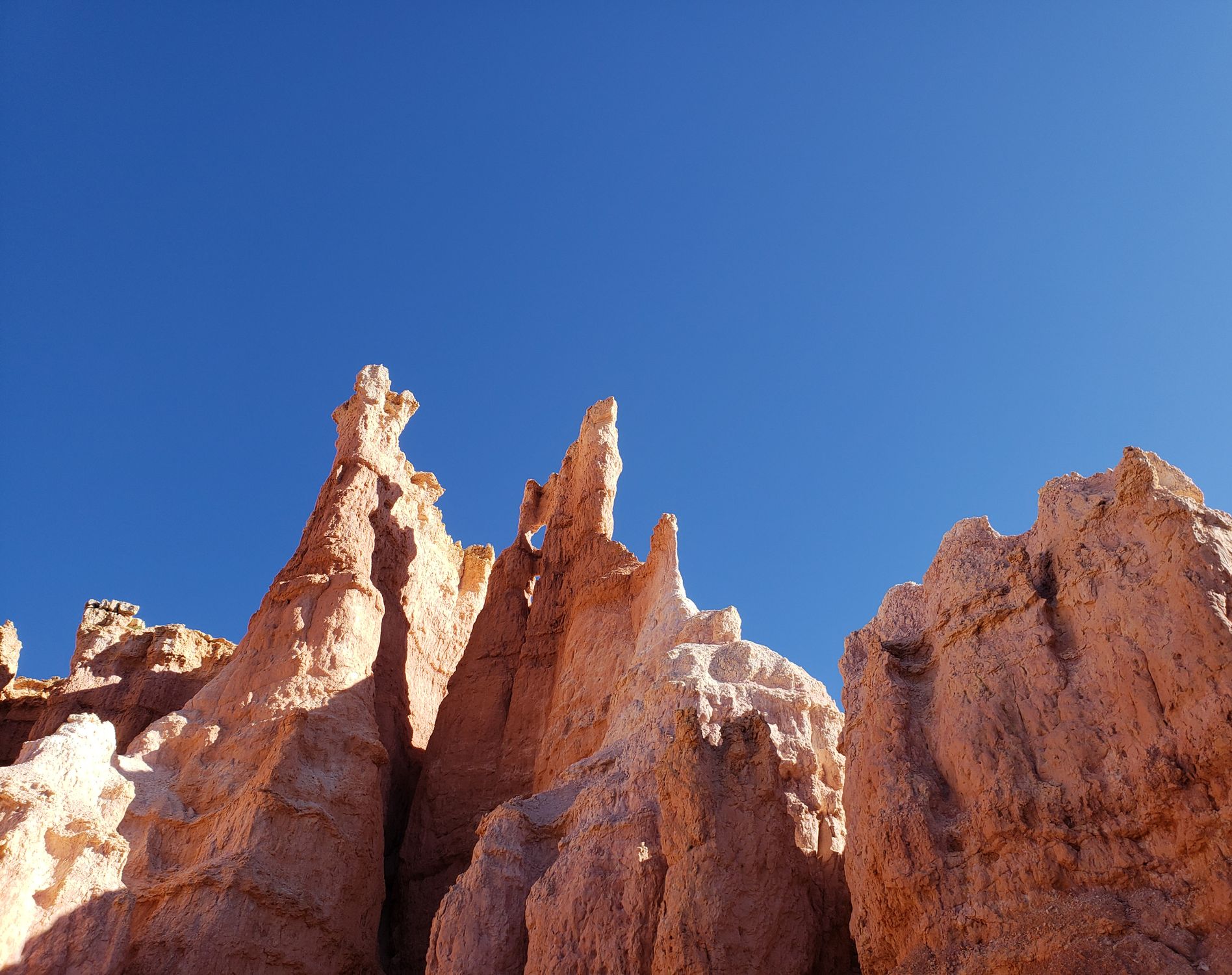 Stunning sandstone formations reach up under a clear blue sky, showcasing natural beauty.