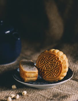 A close-up of a traditional mooncake with detailed designs on a plate, embodying Mid-Autumn Festival spirit.