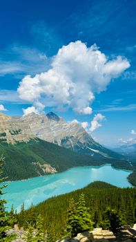 Beautiful summer view of a turquoise lake surrounded by mountains and forests under a clear blue sky.