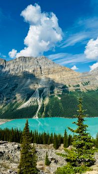 Discover the breathtaking scenery of a turquoise lake surrounded by majestic mountains and lush pines.