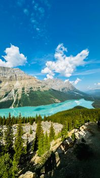 Stunning view of a turquoise mountain lake surrounded by forest and rocky mountains under a clear blue sky.