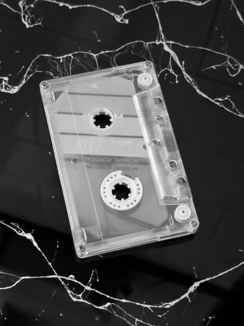 Free Transparent cassette tape resting on a stylish black marble background, highlighting retro music vibes. Stock Photo