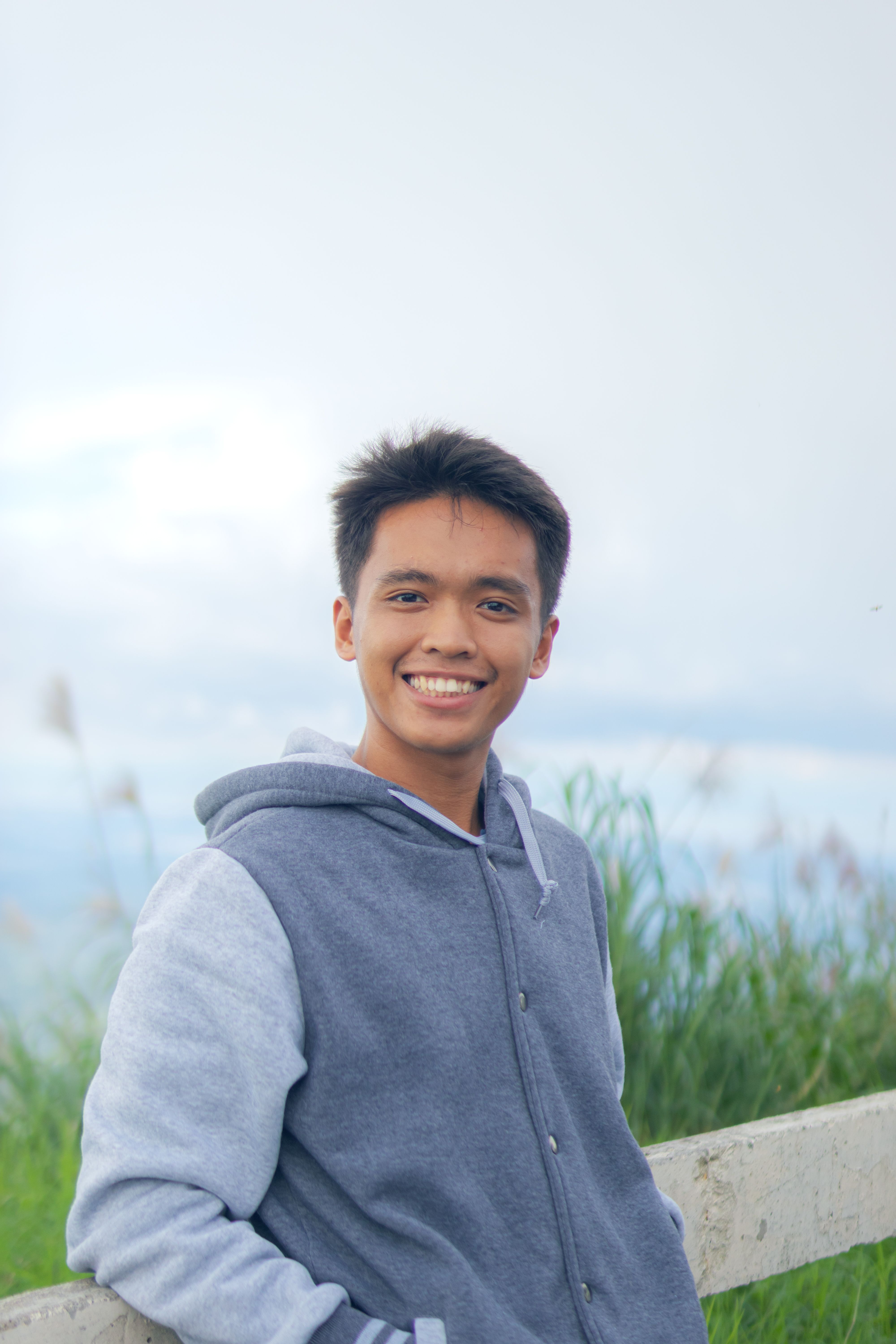 A cheerful young man enjoying a relaxed moment outdoors in casual attire.