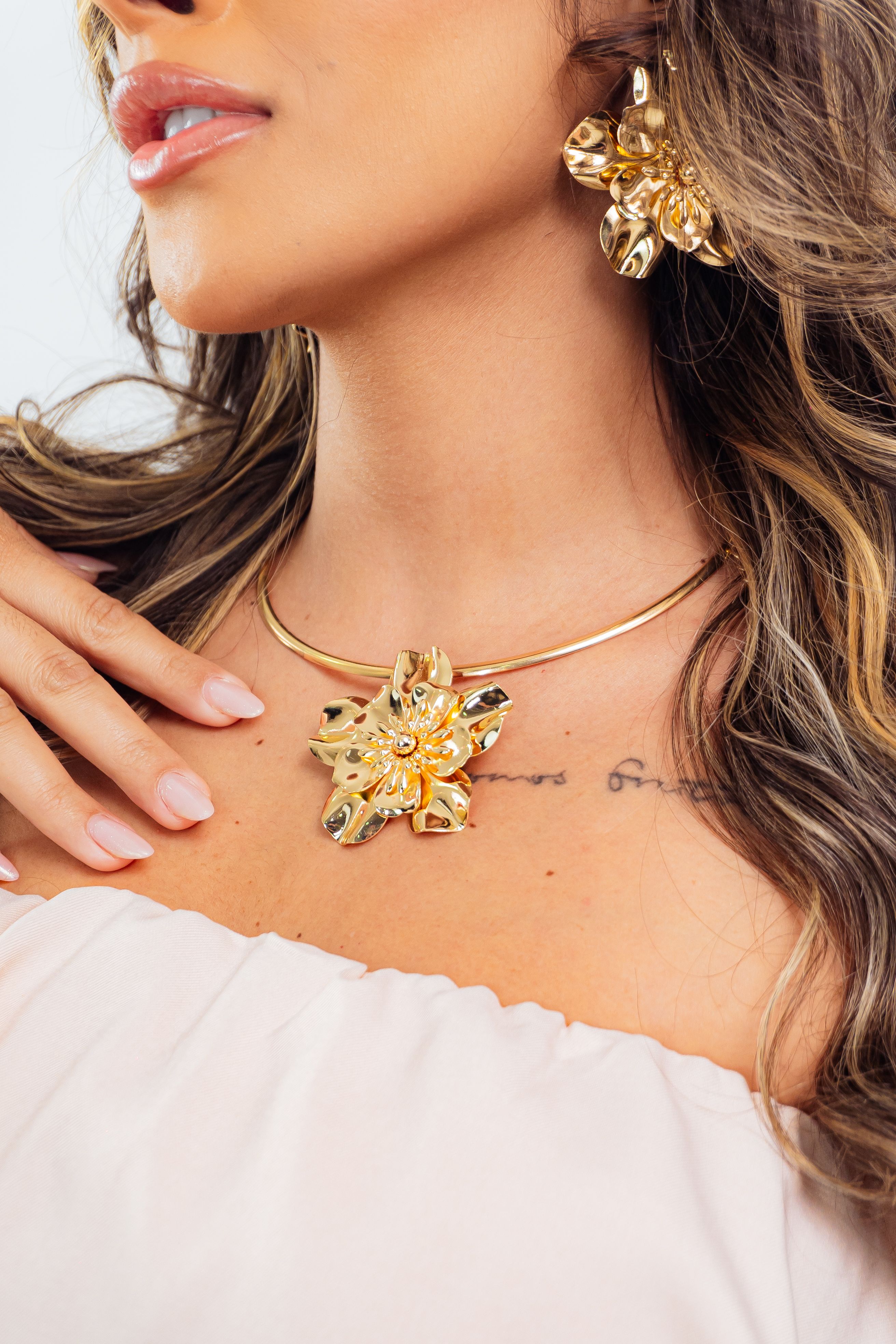 Close-up de uma mulher com colar e brincos de ouro elegantes, exalando luxo e estilo.