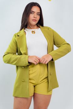 Trendy young woman wearing a green blazer and shorts, exuding confidence and style.