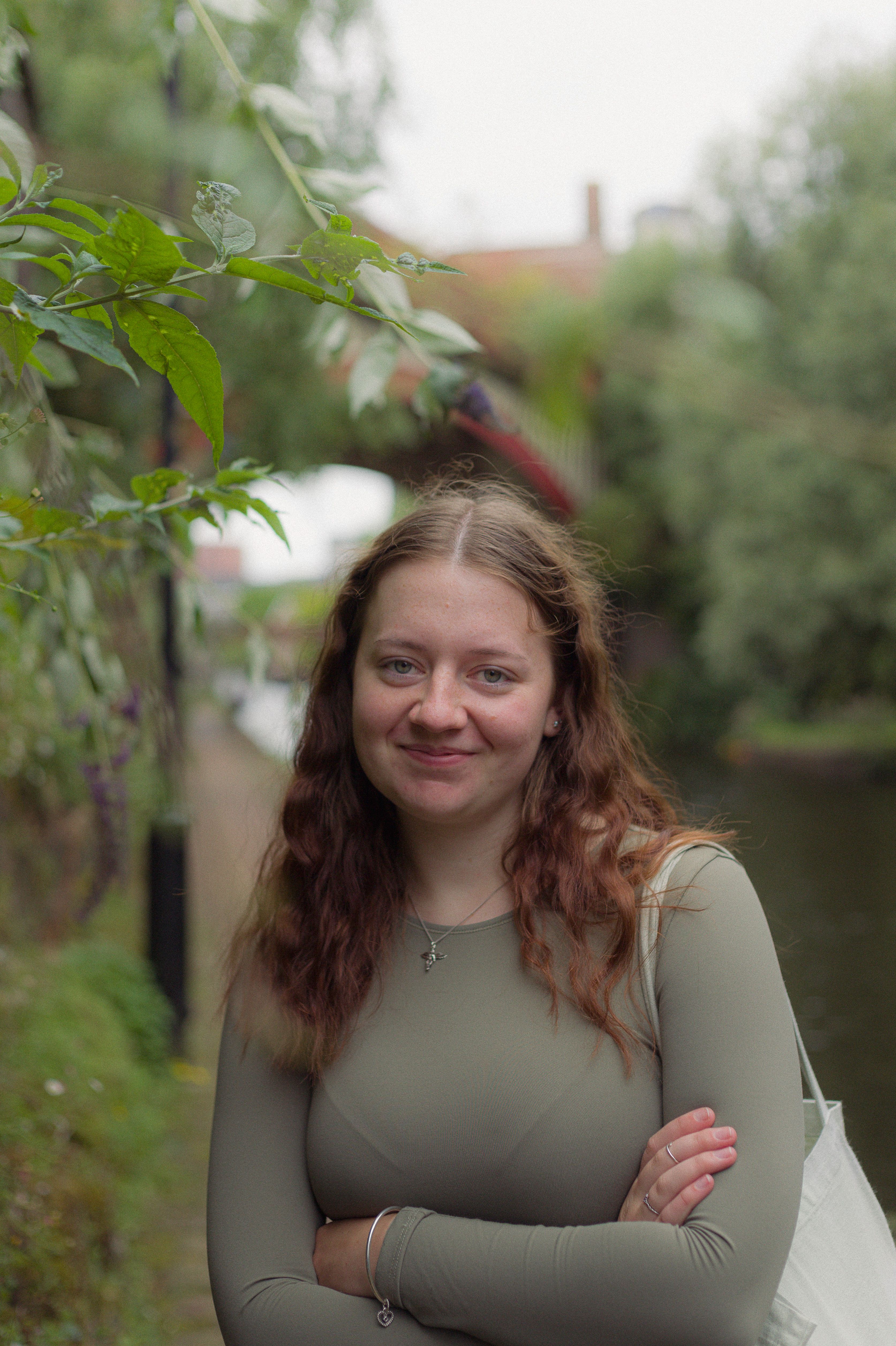Portrait of a young woman smiling in a lush riverside park, showcasing a relaxed and natural scene.