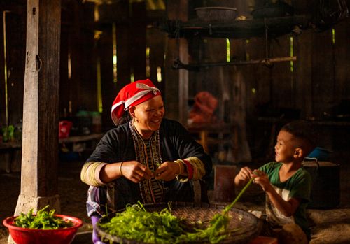 Free A joyful scene of a mother and son preparing vegetables together in a cozy home setting. Stock Photo