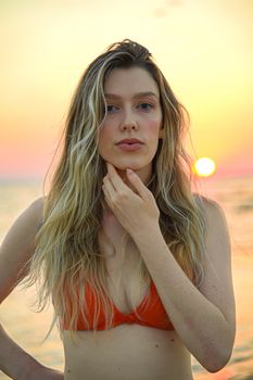 Portrait of a young woman at sunset on the beach, capturing summer beauty.