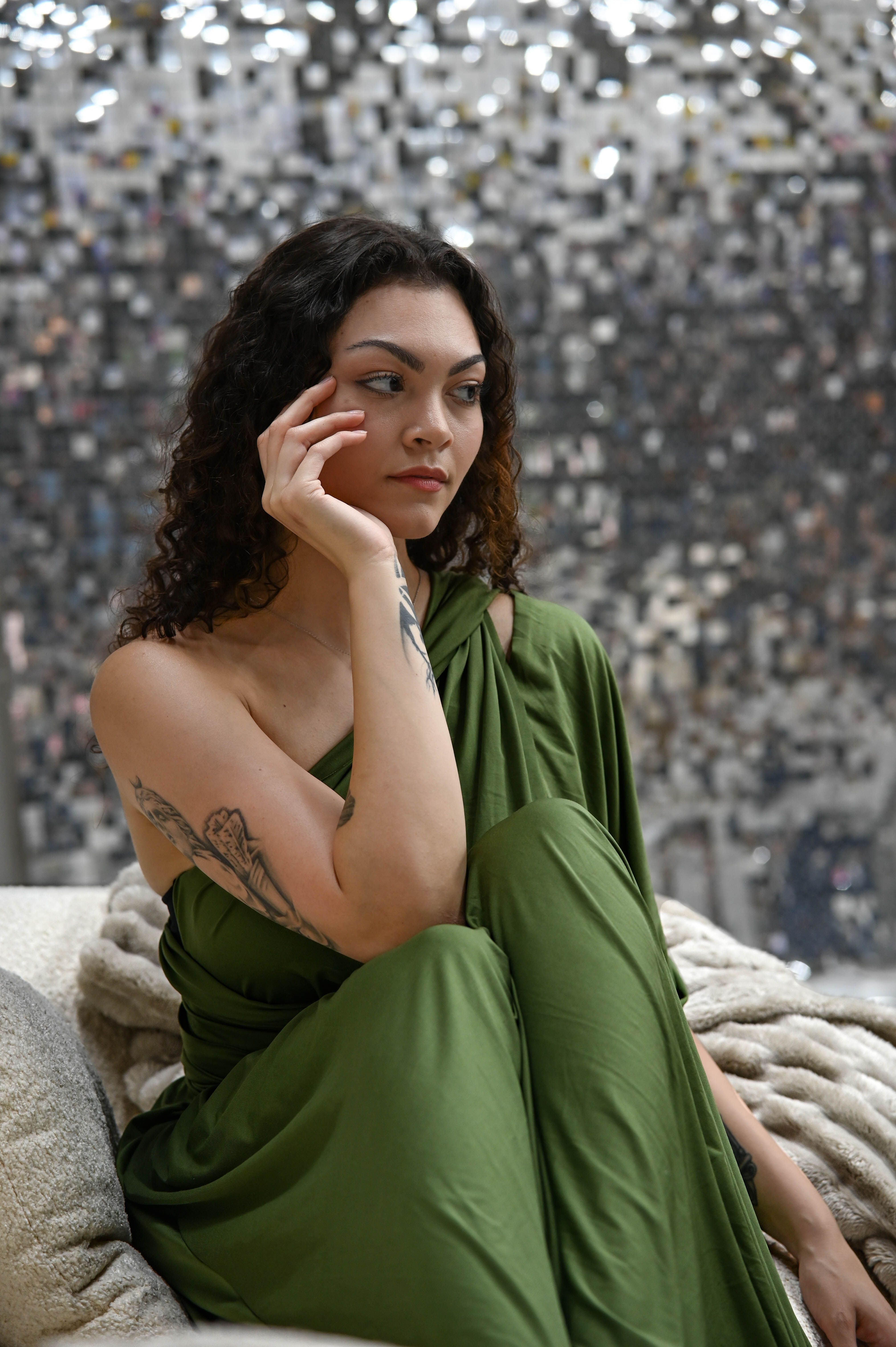 A woman in a green dress sitting on a couch · Free Stock Photo
