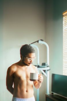 Young man enjoying a quiet moment with coffee by the window, embracing relaxation and morning tranquility.