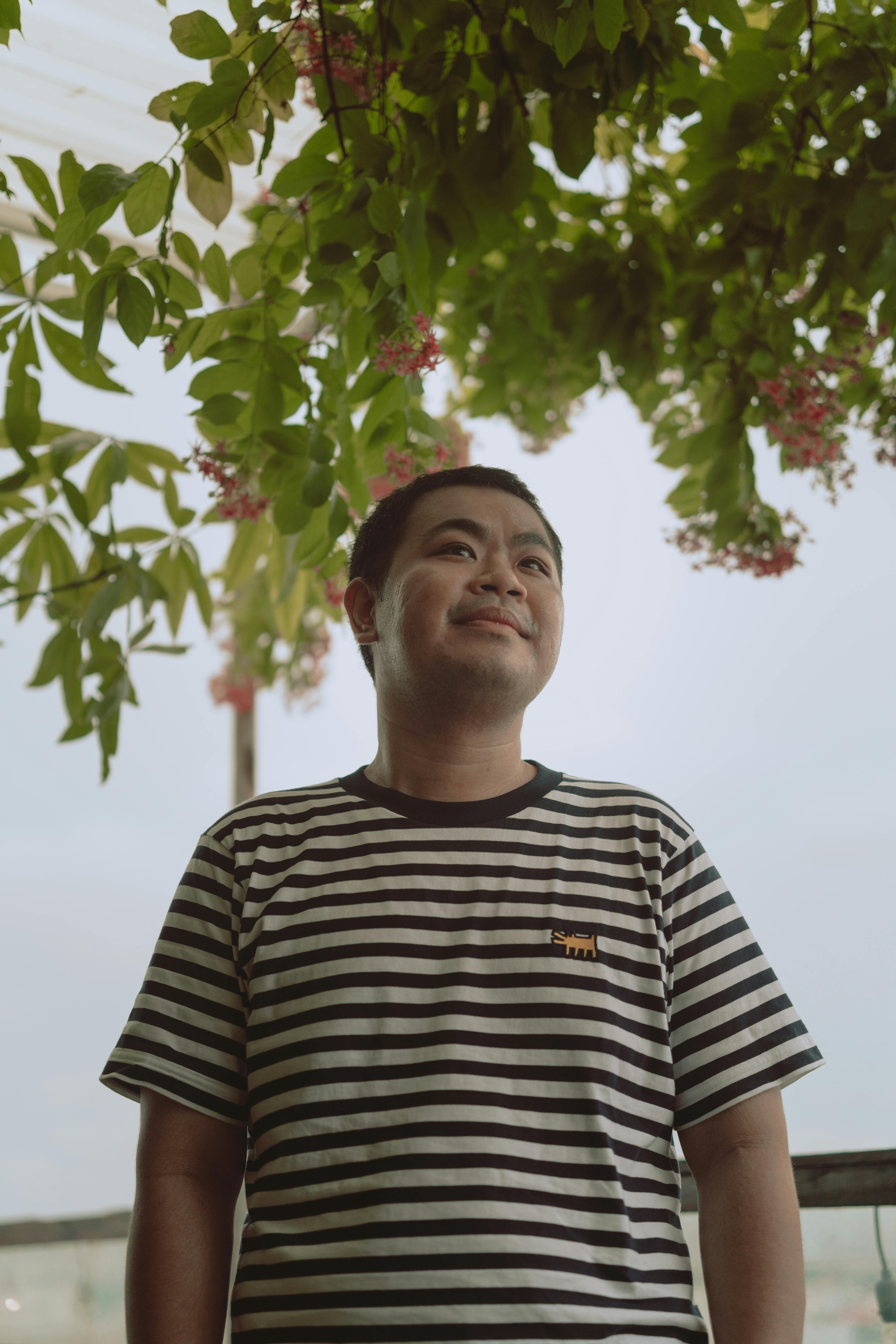 Portrait of a smiling man under leafy vines in Ho Chi Minh City garden.