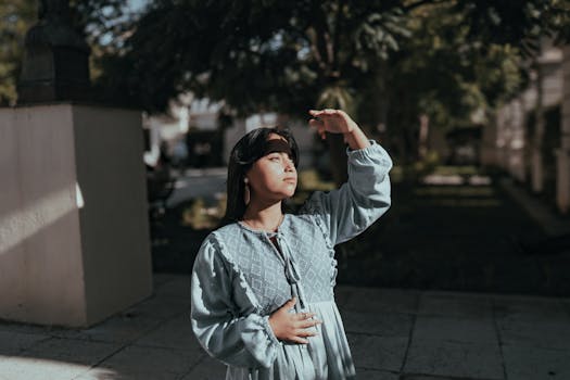 A young woman shielding her eyes from sunlight, wearing traditional attire in a city setting.