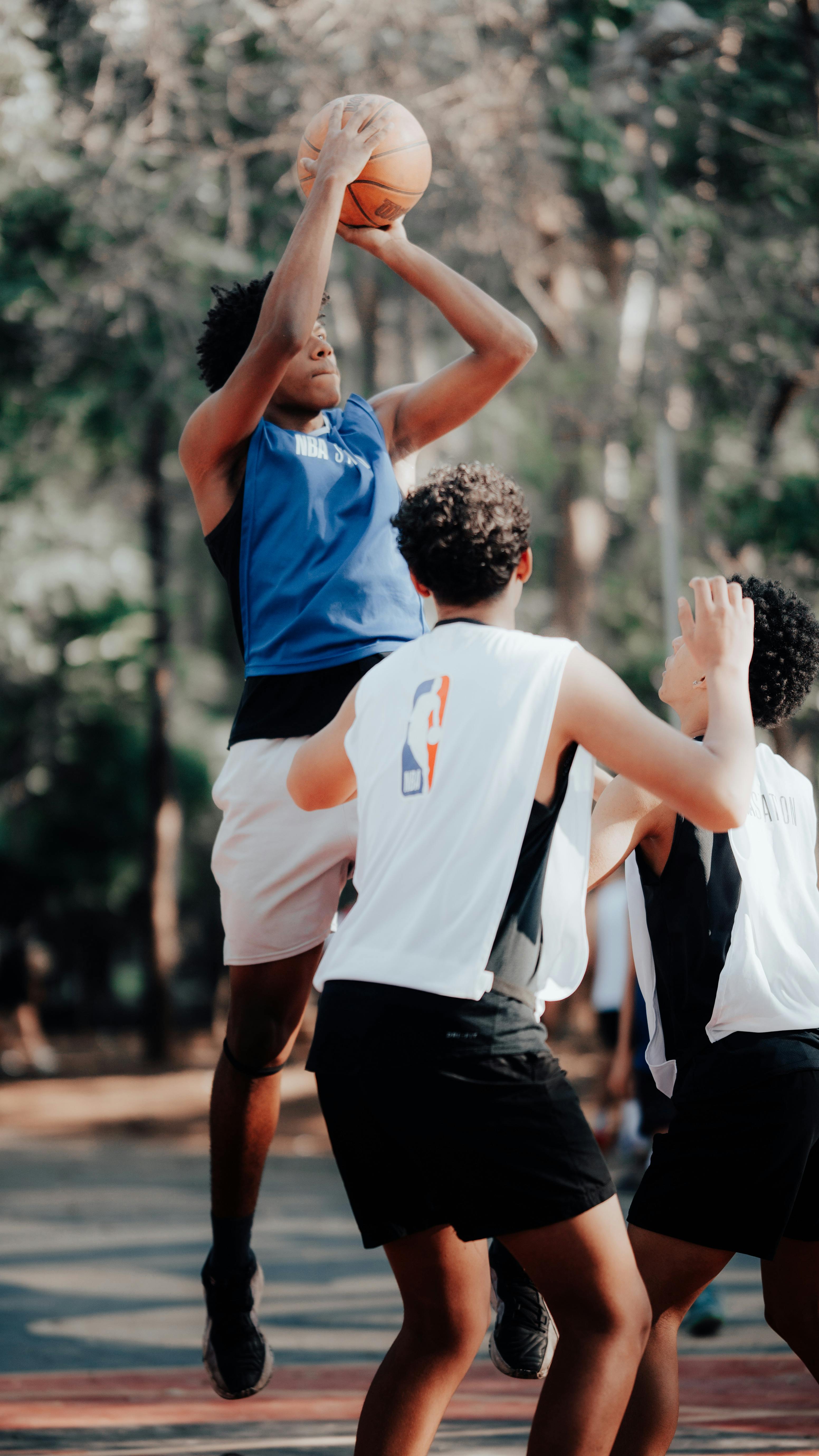 a group of young men playing basketball in the park