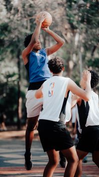 Young men play a competitive basketball game outdoors, showcasing athletic skills.