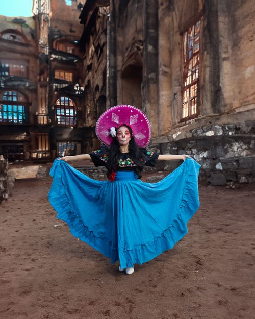 Free Traditional Dia de los Muertos Catrina in vibrant attire posing amidst ancient ruins. Stock Photo