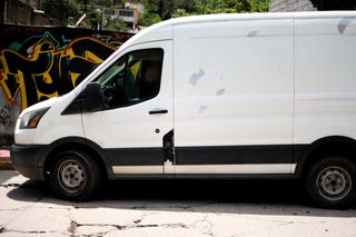 Plain white van with blank sides parked by a graffiti wall