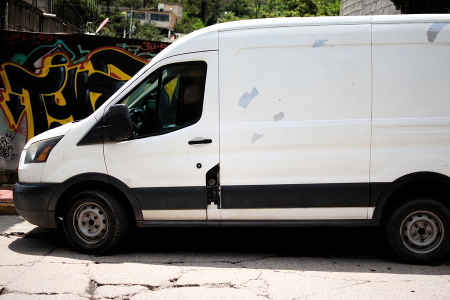 Plain white van with blank sides parked by a graffiti wall