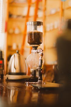 Artistic shot of a vintage coffee siphon in a warm, cozy café setting.