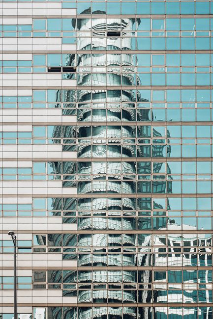 A modern skyscraper reflected in a glass facade in Seoul's urban landscape.