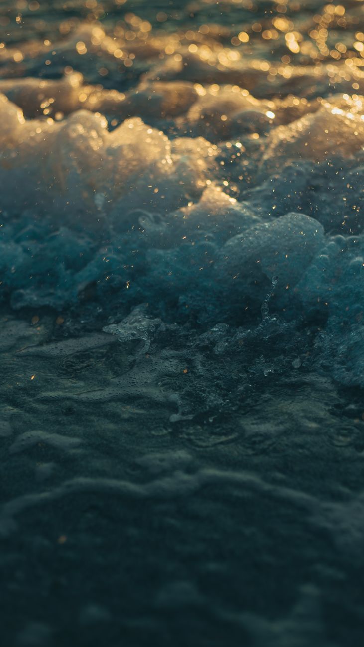 A breathtaking view of ocean waves illuminated by the golden sunset in Corfu, Greece.
