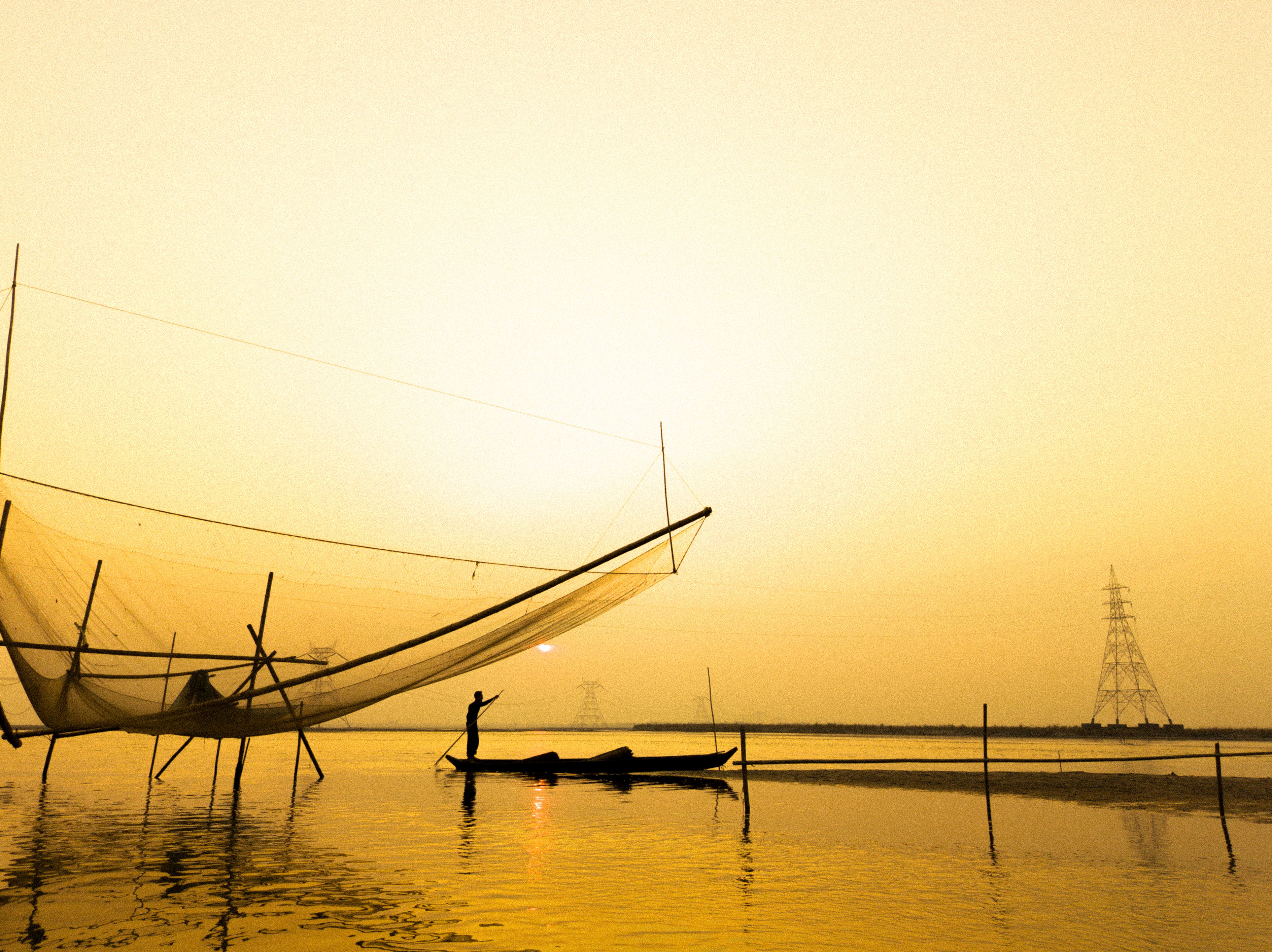 Cantilevered Chinese fishing nets silhouetted against the sunset at Fort Kochi