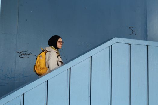 A woman with a yellow backpack is walking up stairs