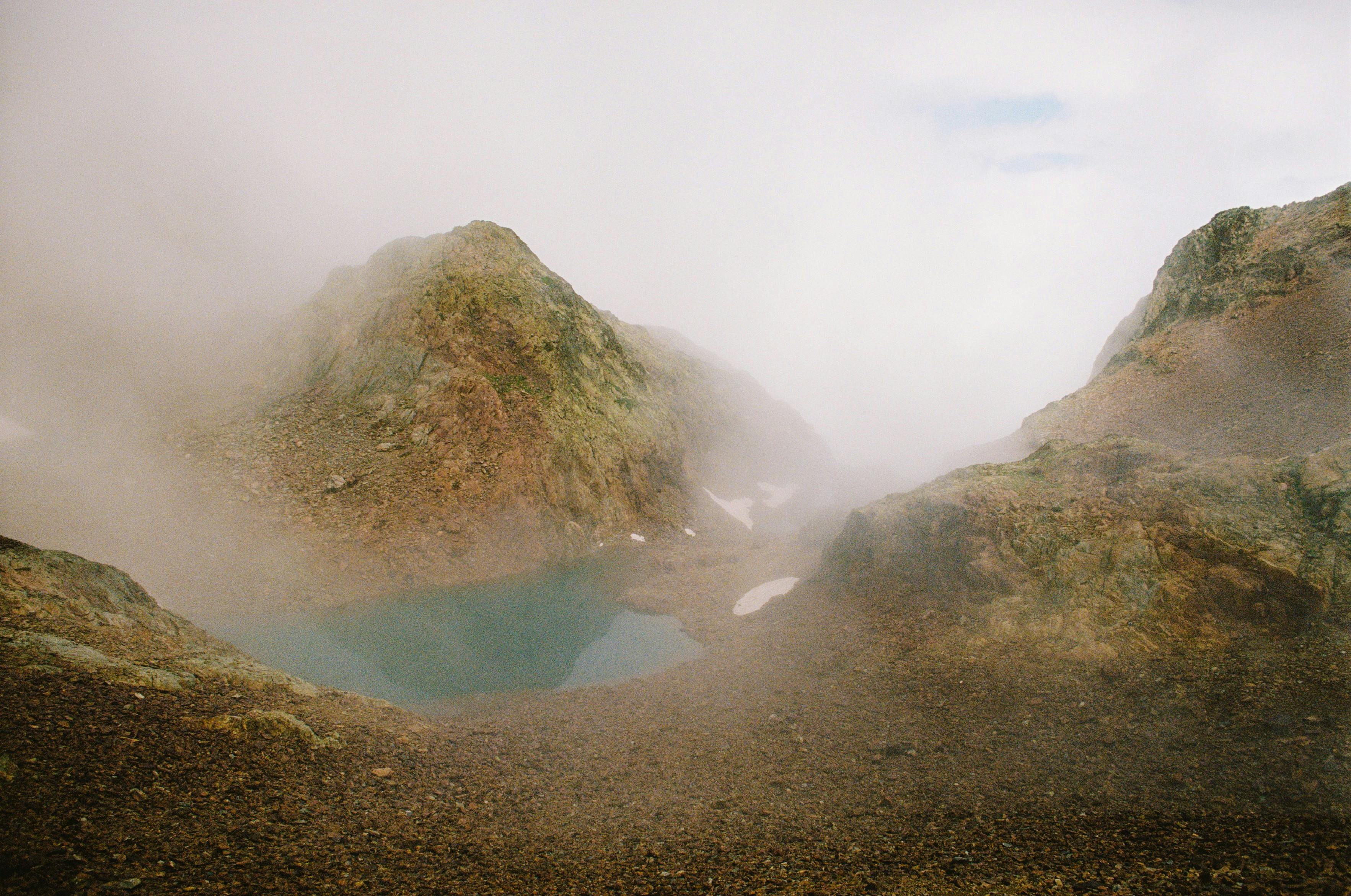 A serene misty mountain scene with a tranquil lake surrounded by rocky terrain in Spain.