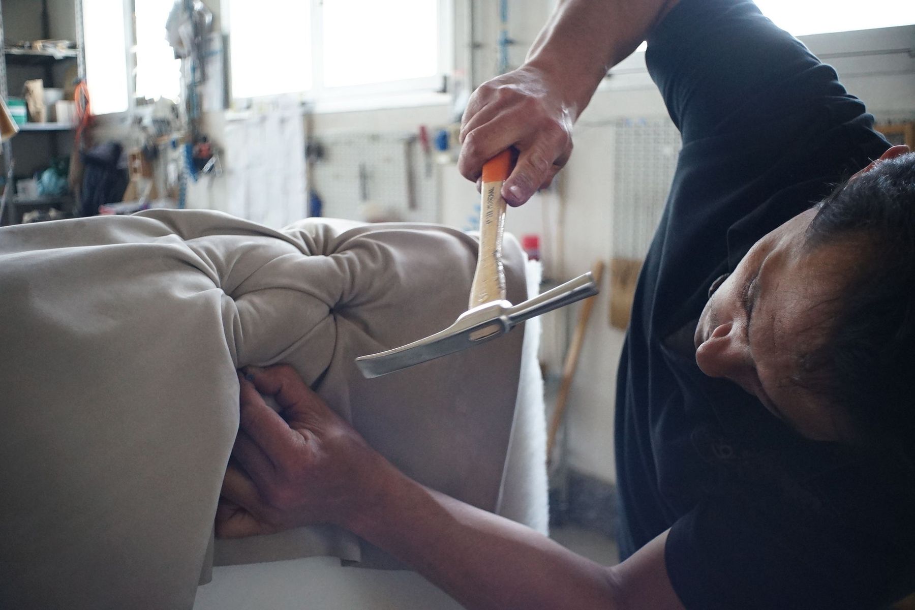 Upholsterer carefully securing fabric to a tufted furniture piece