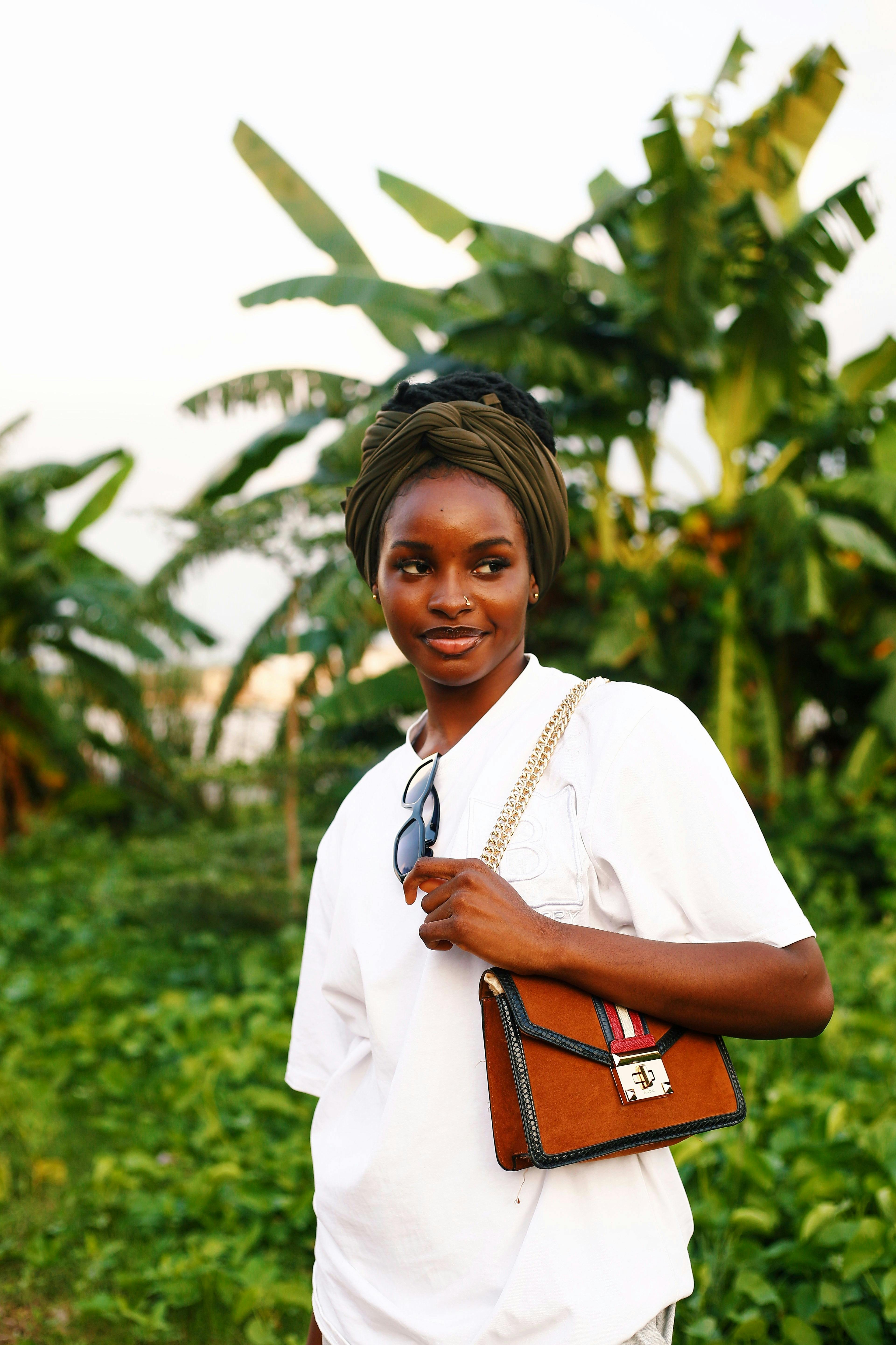 A cheerful woman enjoys a sunny day in a lush green setting, exuding happiness and relaxation.