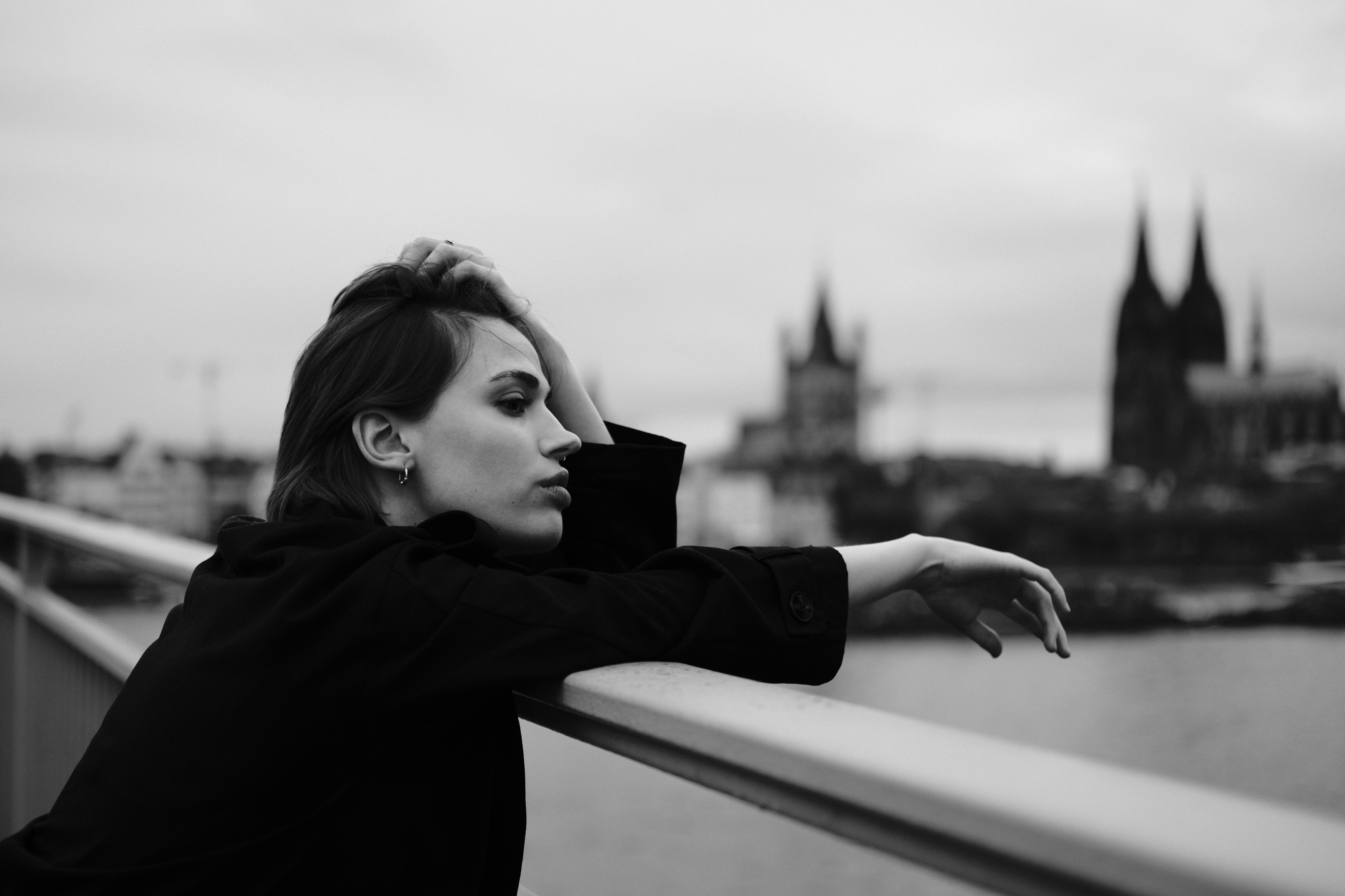 A woman leaning over a railing with a city in the background · Free ...