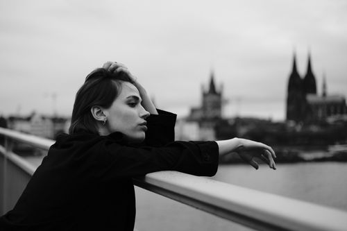 Free Moody black and white portrait of a woman on a bridge with Cologne Cathedral in the background. Stock Photo