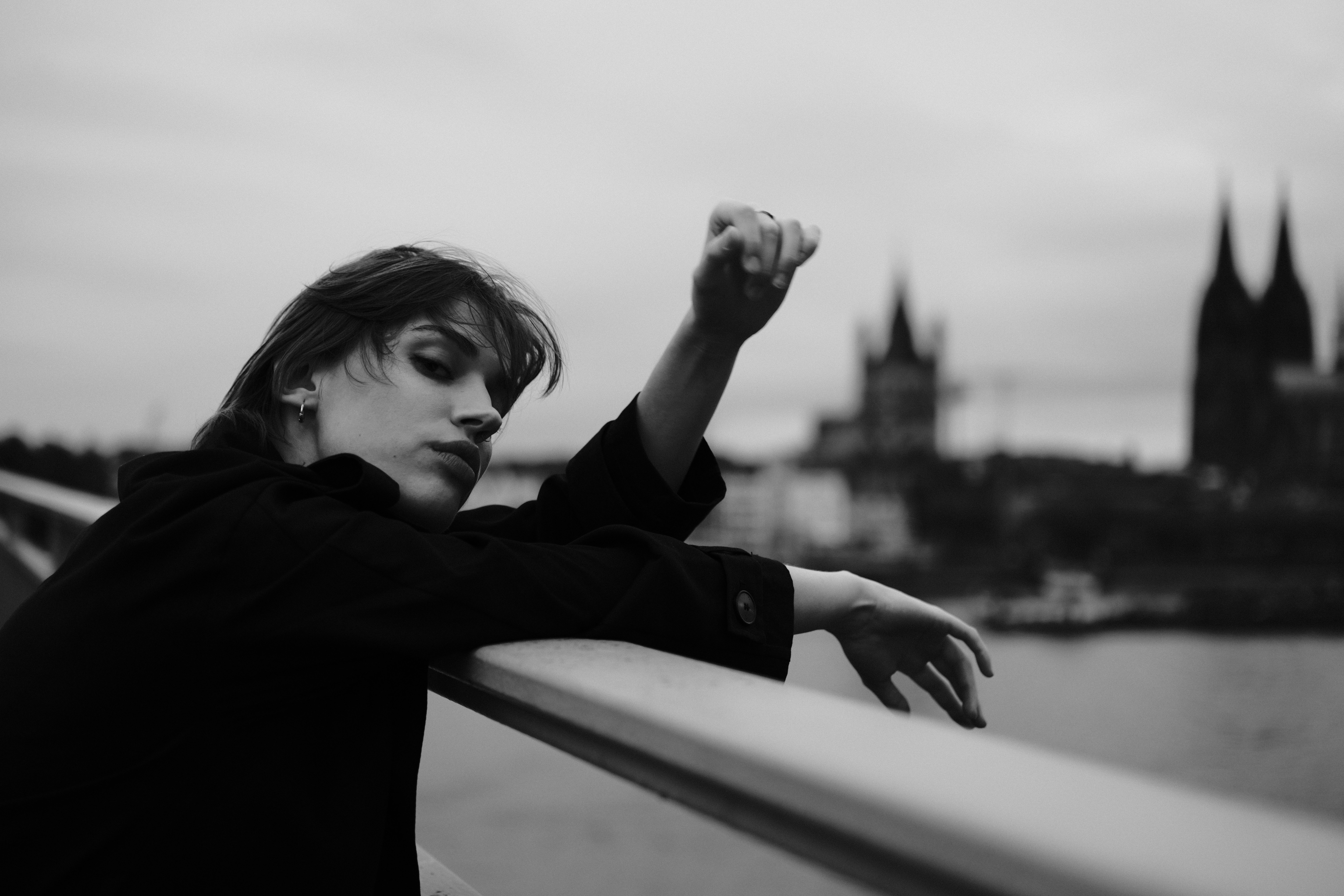 A woman leaning over a railing with a city in the background · Free ...