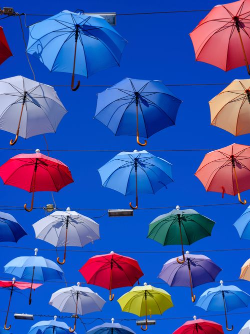 Free Vibrant umbrellas hanging in the air against a clear blue sky in Türkiye. Stock Photo