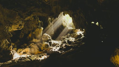 Free Atmospheric cave scene with sunlight beams illuminating rocky interior formations. Stock Photo