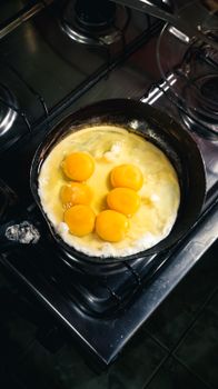 Close-up of multiple eggs frying in a pan on a stove, showcasing morning breakfast preparation.
