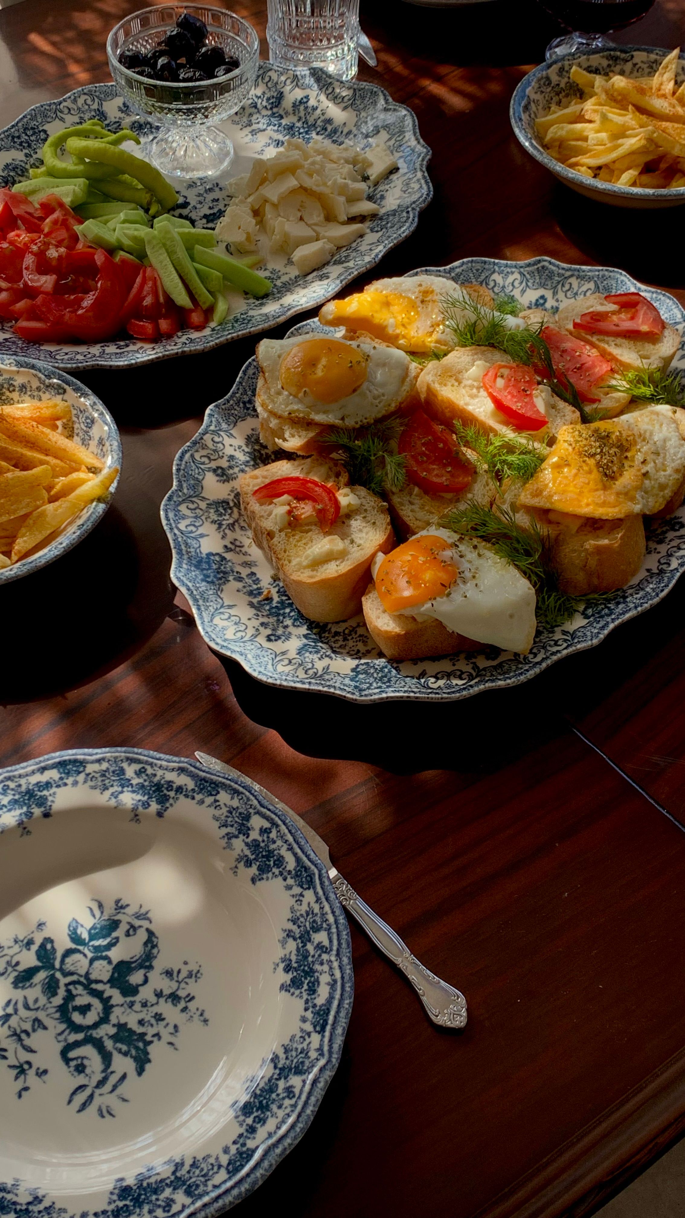 A vibrant traditional breakfast spread featuring eggs, veggies, and fries on decorative plates.