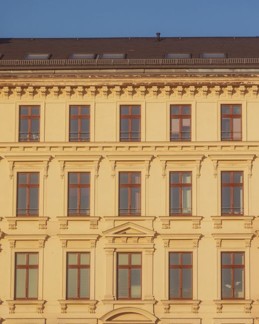 Close-up of a classic building's facade with decorative architecture and windows, bathed in light.