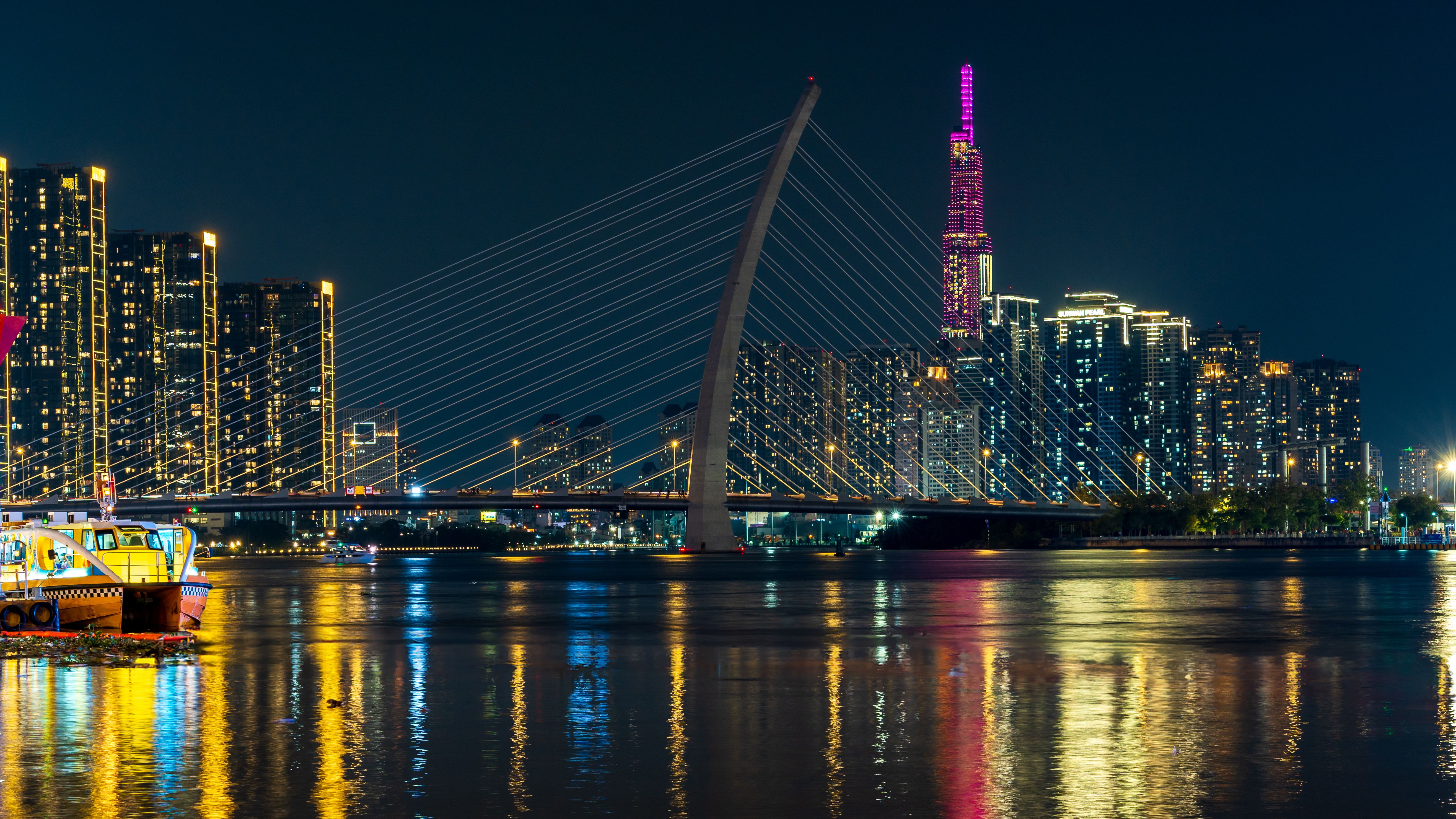 A city skyline with a bridge and boats at night · Free Stock Photo