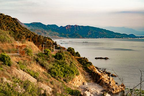 Free Tranquil seaside view of mountains and coastline at dusk, perfect for nature and travel themes. Stock Photo