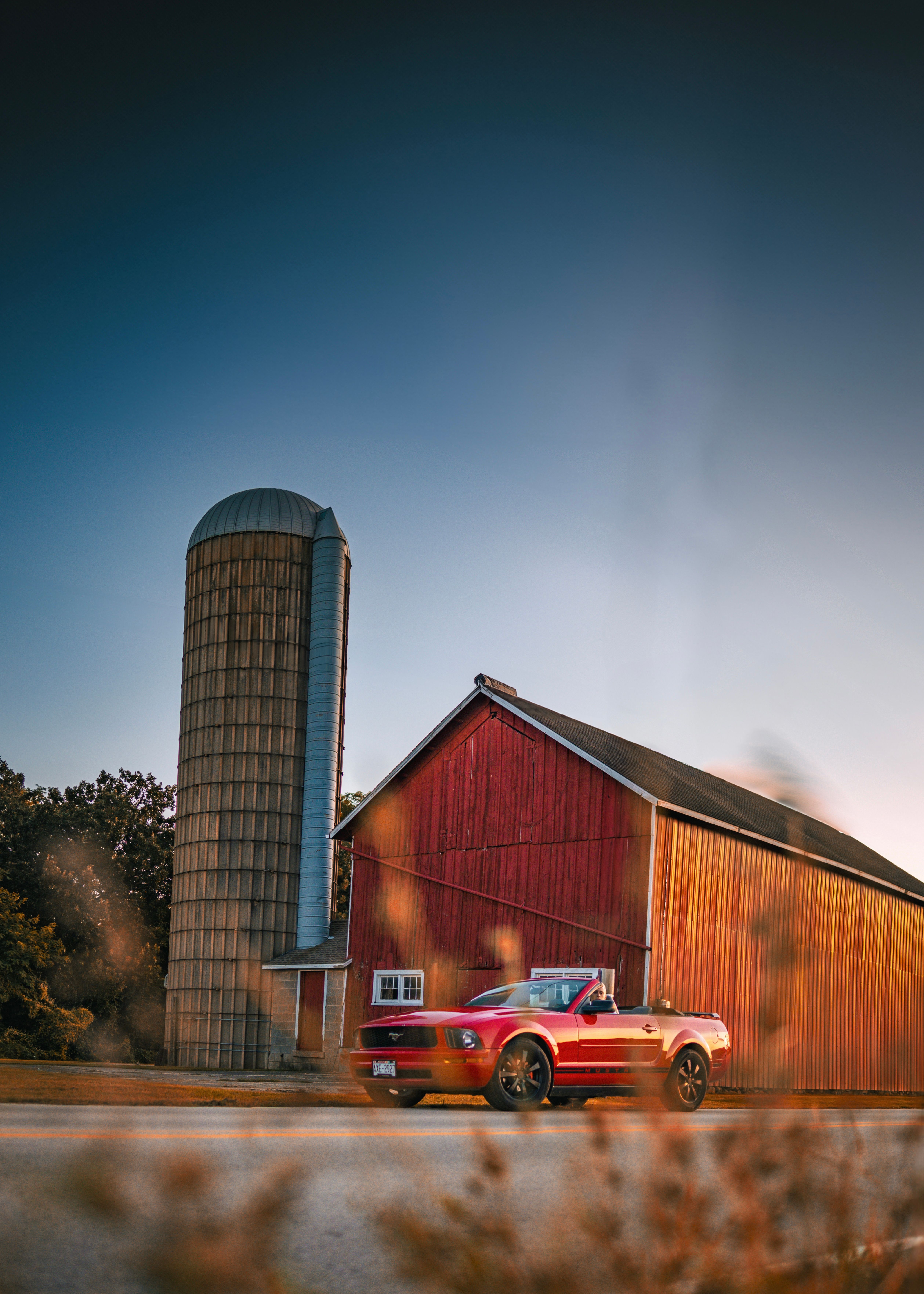 A red car is parked in front of a barn · Free Stock Photo