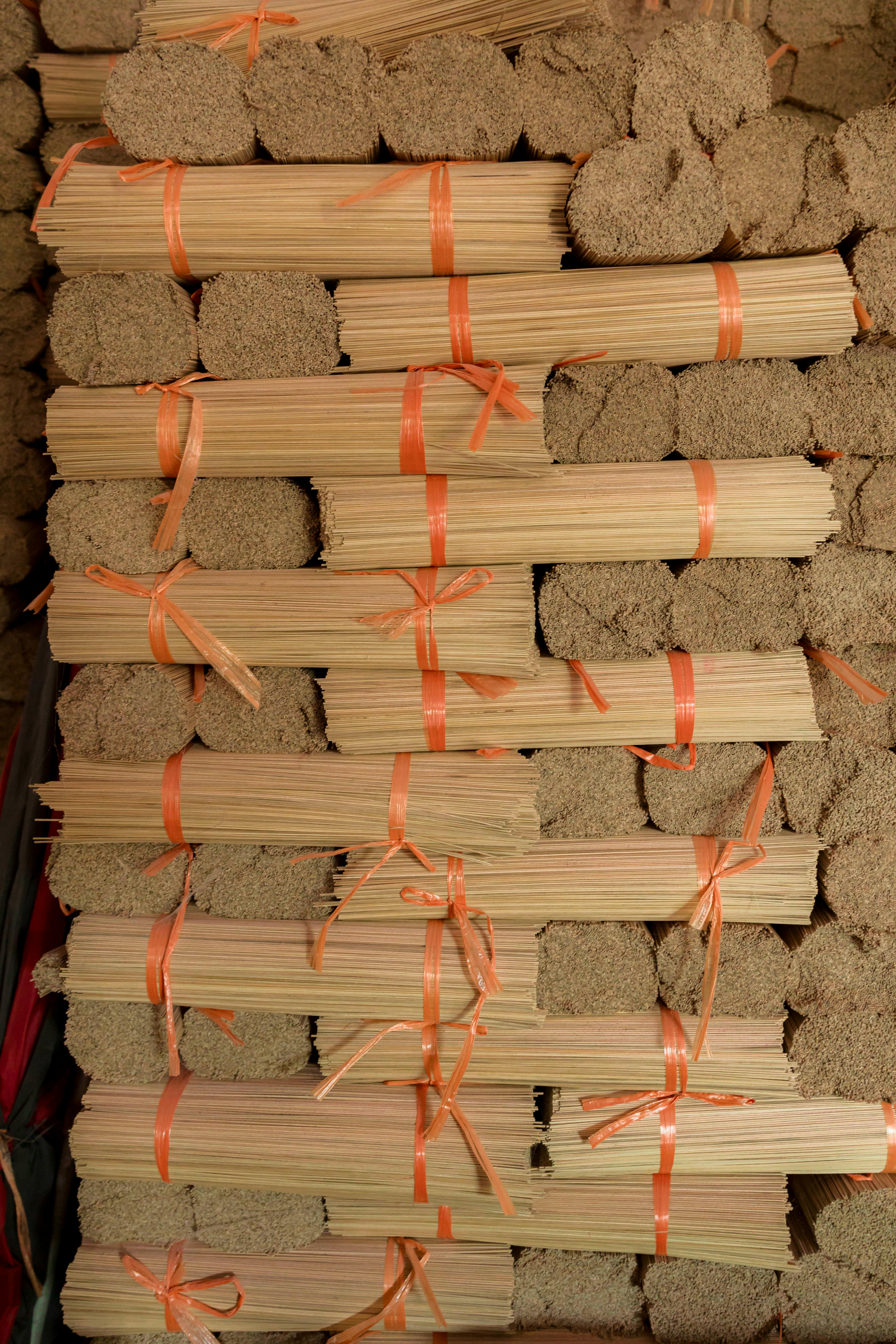 Bundles of neatly stacked traditional incense sticks tied with orange ribbons, ready for shipping.