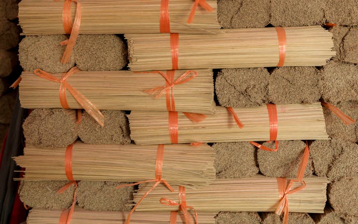 Bundles of neatly stacked traditional incense sticks tied with orange ribbons, ready for shipping.