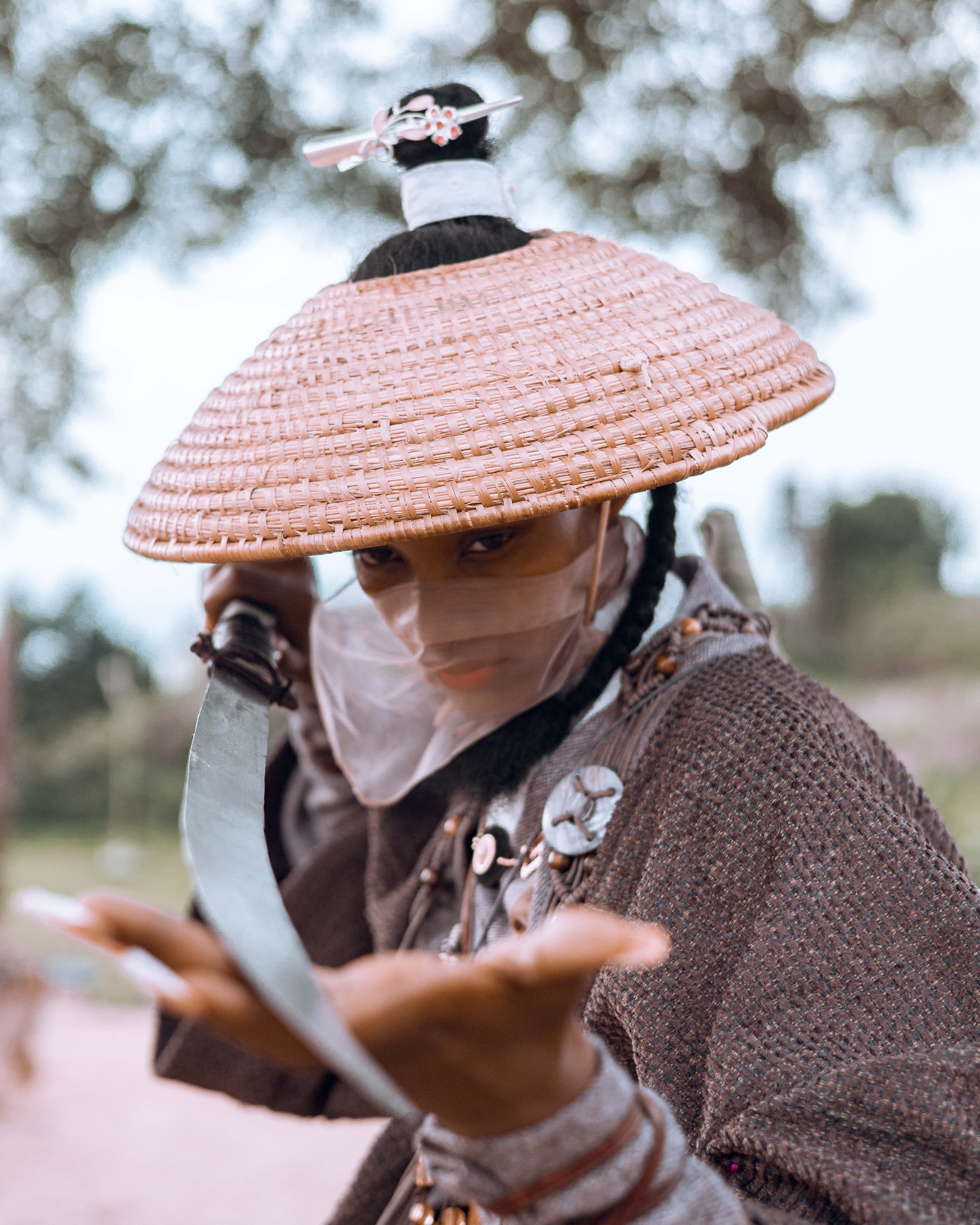 A fierce warrior woman in traditional armor holding a sword outdoors, embodying strength.