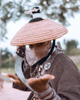 A fierce warrior woman in traditional armor holding a sword outdoors, embodying strength.