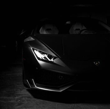 Dark, moody capture of a sleek, black sports car highlighting its elegant design.