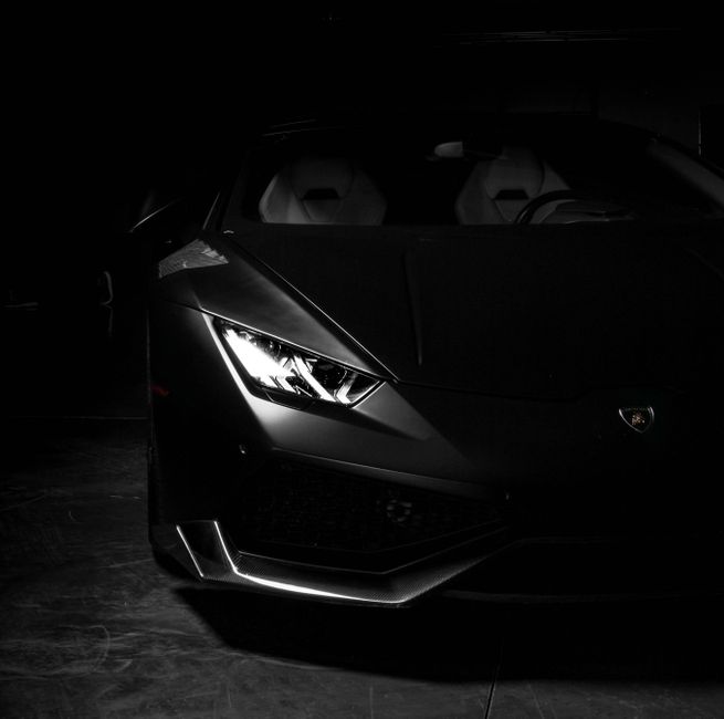 Dark, moody capture of a sleek, black sports car highlighting its elegant design.