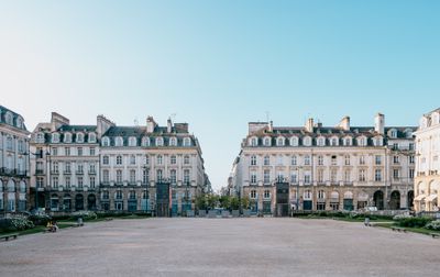 Architecture classique sur la place du Parlement de Rennes sous un ciel bleu dégagé.